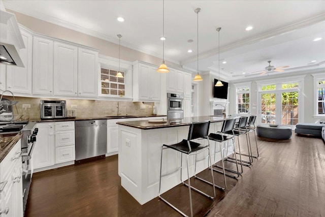1332 W Wellington Ave, Chicago, IL 60657 - kitchen with stainless steel appliances, wall chimney exhaust hood, dark countertops, dark wood finished floors, and backsplash