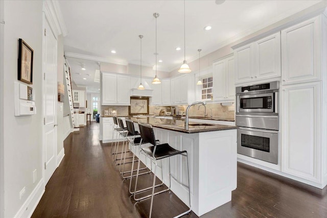 1332 W Wellington Ave, Chicago, IL 60657 - kitchen with oven, dark countertops, a sink, dark wood finished floors, and white cabinets