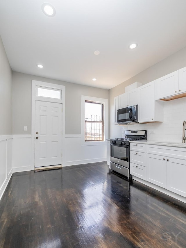 3651 W Grenshaw St, Chicago, IL 60624 - kitchen featuring gas range, black microwave, dark wood-type flooring, white cabinets, and wainscoting