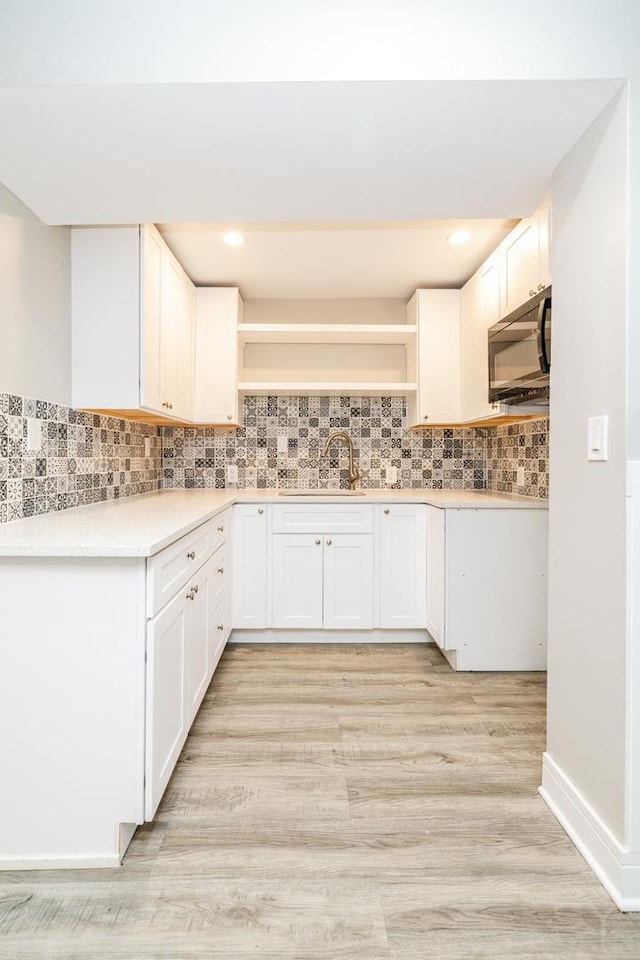 3651 W Grenshaw St, Chicago, IL 60624 - kitchen featuring black microwave, open shelves, white cabinetry, light wood finished floors, and backsplash