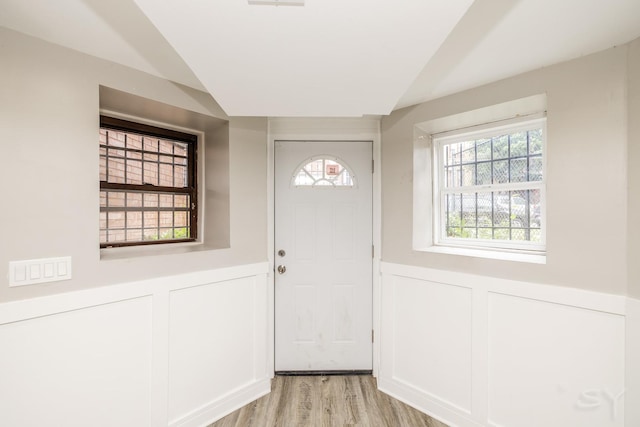 3651 W Grenshaw St, Chicago, IL 60624 - doorway to outside featuring a decorative wall, wainscoting, lofted ceiling, and light wood finished floors