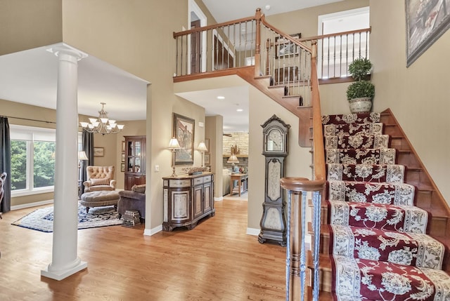 2559 Bird Ln, Batavia, IL 60510 - staircase featuring ornate columns, wood finished floors, a towering ceiling, a chandelier, and baseboards