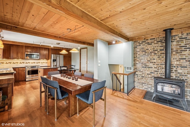 218 S Owen St, Mount Prospect, IL 60056 - dining space with light wood-style floors, a wood stove, a wooden ceiling with exposed beams, and rail lighting
