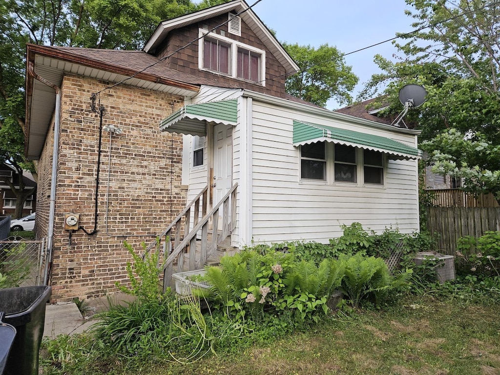 view of front of house featuring roof with shingles and brick siding