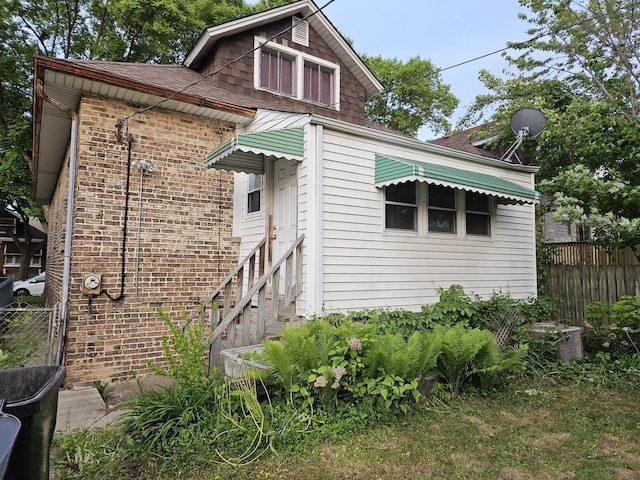 view of front of house featuring roof with shingles and brick siding