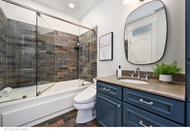 2015 N Howe St, Chicago, IL 60614 - bathroom featuring vanity, shower / bath combination with glass door, toilet, stone finish floors, and recessed lighting