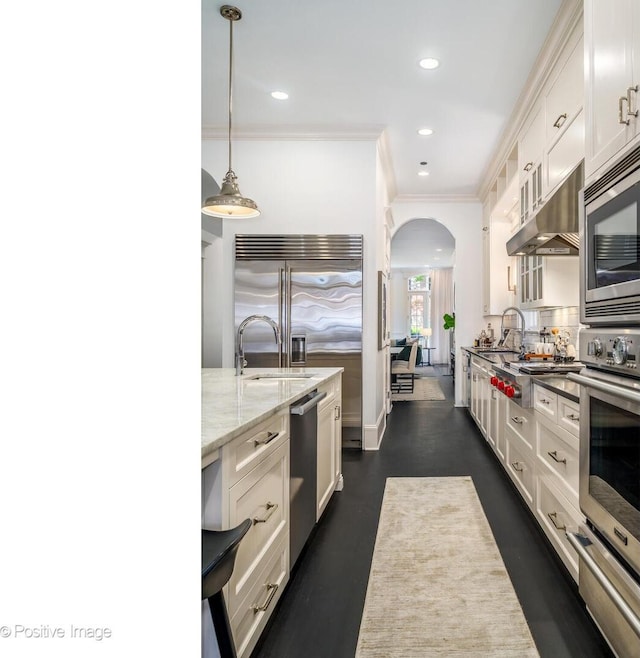 2015 N Howe St, Chicago, IL 60614 - kitchen with built in appliances, arched walkways, ornamental molding, white cabinets, and light stone counters