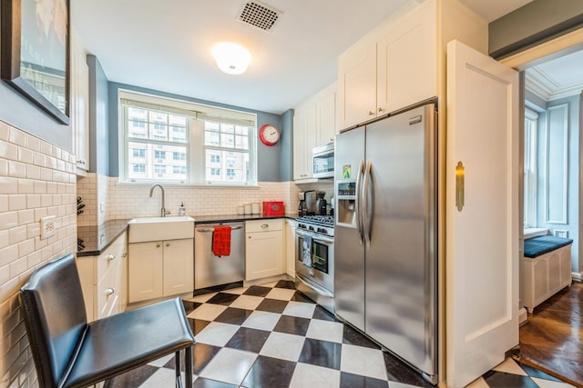 421 W Melrose St Unit 10B, Chicago, IL 60657 - kitchen with stainless steel appliances, a sink, dark countertops, decorative backsplash, and white cabinetry