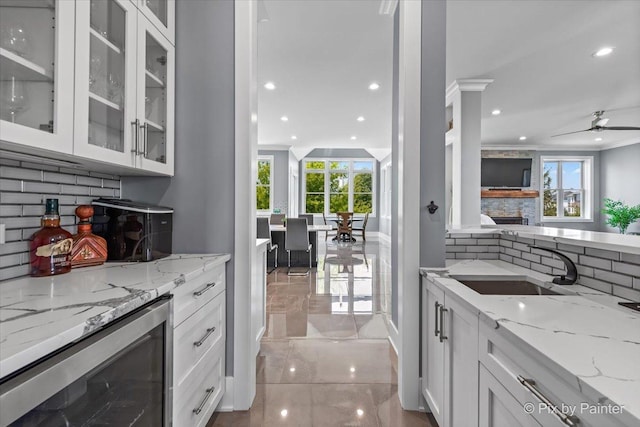 1044 Redbud Ln, Sugar Grove, IL 60554 - kitchen with backsplash, a stone fireplace, white cabinetry, glass insert cabinets, and recessed lighting