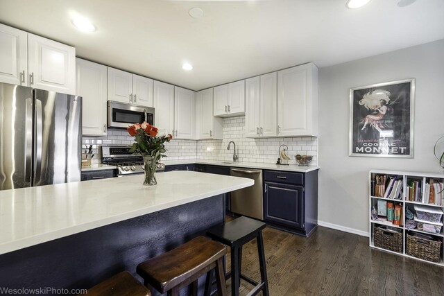 3315 N Racine Ave Unit E, Chicago, IL 60657 - kitchen featuring stainless steel appliances, white cabinets, a breakfast bar, tasteful backsplash, and recessed lighting