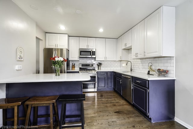 3315 N Racine Ave Unit E, Chicago, IL 60657 - kitchen featuring appliances with stainless steel finishes, a breakfast bar, dark wood-style floors, white cabinetry, and recessed lighting