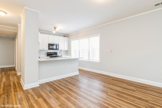 7363 N Damen Ave Unit 302, Chicago, IL 60645 - kitchen with black microwave, range, crown molding, white cabinetry, and baseboards