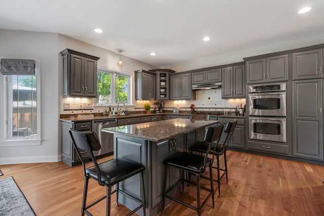 785 N Emroy Ave, Elmhurst, IL 60126 - kitchen featuring appliances with stainless steel finishes, a kitchen bar, light wood-style flooring, decorative backsplash, and under cabinet range hood