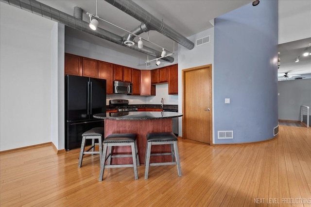 1673 Town Center St Unit 1673, Aurora, IL 60504 - kitchen with stainless steel appliances, a towering ceiling, dark countertops, a breakfast bar area, and light wood-style flooring