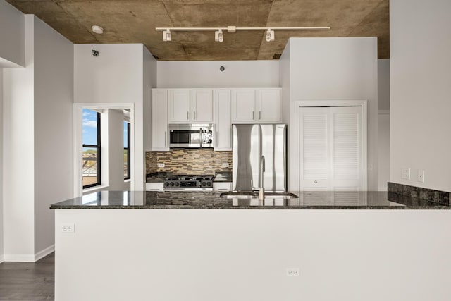 1122 W Catalpa Ave Unit 418, Chicago, IL 60640 - kitchen with appliances with stainless steel finishes, track lighting, dark stone countertops, tasteful backsplash, and a peninsula
