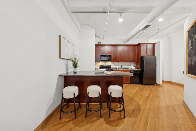 633 S Plymouth Ct Unit 607, Chicago, IL 60605 - kitchen featuring black appliances, a sink, light wood-style flooring, a kitchen bar, and a peninsula