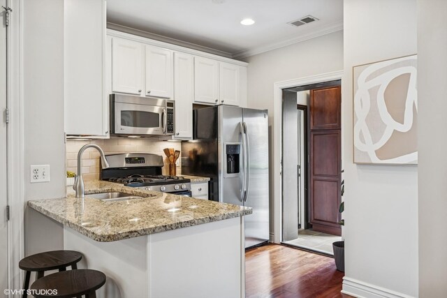 3539 N Lakewood Ave Unit 3, Chicago, IL 60657 - kitchen with stainless steel appliances, a sink, crown molding, a breakfast bar, and white cabinets