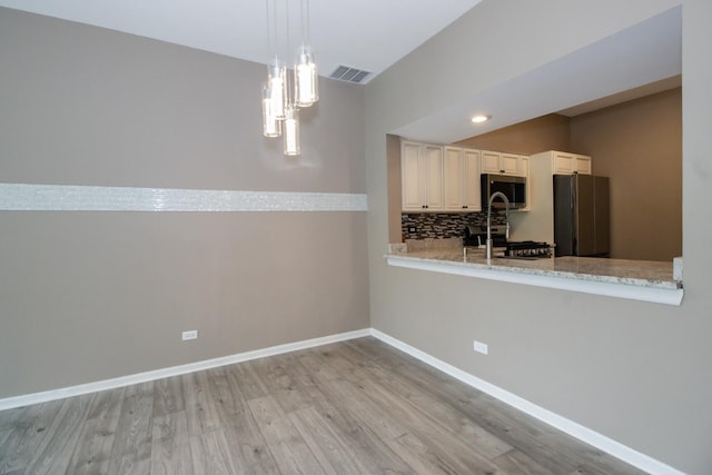 218 Partridge Ct, Algonquin, IL 60102 - kitchen with appliances with stainless steel finishes, light wood-style flooring, tasteful backsplash, a peninsula, and hanging light fixtures