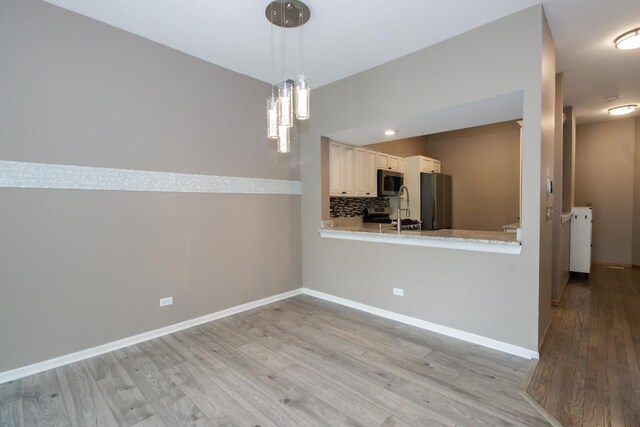 218 Partridge Ct, Algonquin, IL 60102 - kitchen featuring stainless steel appliances, light wood-style flooring, decorative backsplash, pendant lighting, and a peninsula