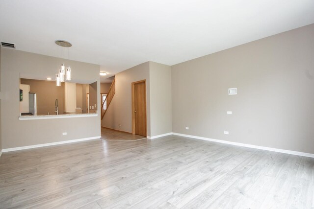 218 Partridge Ct, Algonquin, IL 60102 - unfurnished living room with light wood-style flooring, stairway, and a chandelier