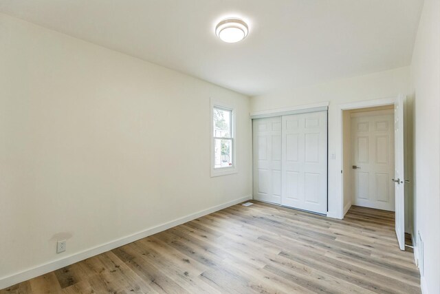 313 Grand Blvd, Loves Park, IL 61111 - unfurnished bedroom with light wood finished floors, baseboards, and a closet