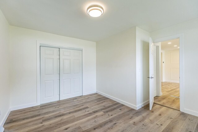 313 Grand Blvd, Loves Park, IL 61111 - unfurnished bedroom with light wood-style floors, baseboards, and a closet