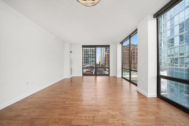 233 E 13th St Unit 601, Chicago, IL 60605 - empty room featuring a city view, light wood-style flooring, baseboards, and floor to ceiling windows