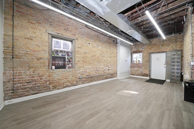 4854 W Addison St, Chicago, IL 60641 - below grade area featuring baseboards, brick wall, and wood finished floors
