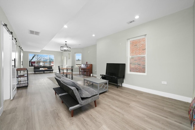 4854 W Addison St, Chicago, IL 60641 - living room with a barn door, light wood-style flooring, baseboards, recessed lighting, and a chandelier