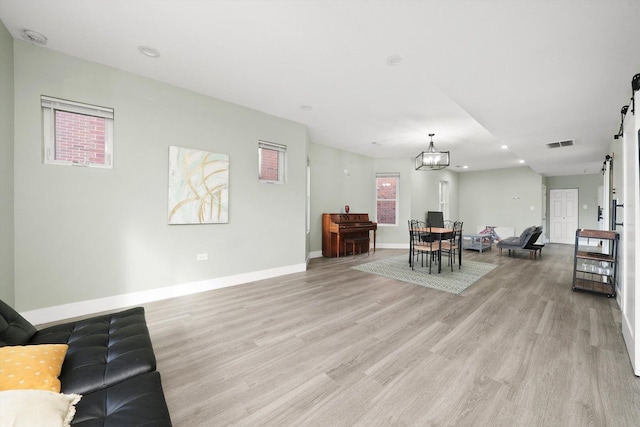 4854 W Addison St, Chicago, IL 60641 - living room with light wood finished floors, baseboards, a barn door, recessed lighting, and a chandelier