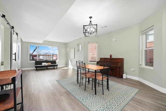 4854 W Addison St, Chicago, IL 60641 - dining room featuring wood finished floors, baseboards, a chandelier, and a barn door