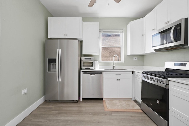 4854 W Addison St, Chicago, IL 60641 - kitchen with appliances with stainless steel finishes, a sink, white cabinetry, light wood finished floors, and a ceiling fan