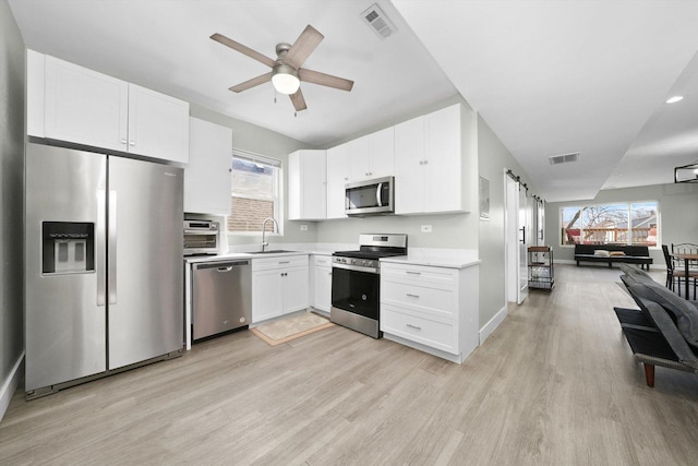 4854 W Addison St, Chicago, IL 60641 - kitchen featuring appliances with stainless steel finishes, a sink, light wood-type flooring, open floor plan, and light countertops