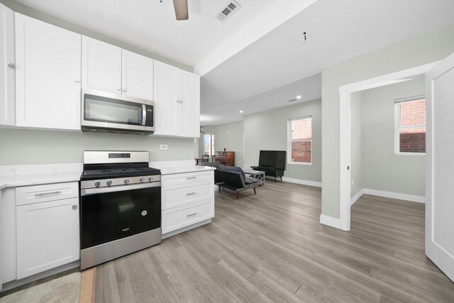 4854 W Addison St, Chicago, IL 60641 - kitchen with stainless steel appliances, light wood-type flooring, white cabinetry, a ceiling fan, and baseboards