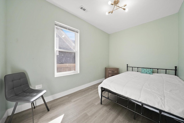 4854 W Addison St, Chicago, IL 60641 - bedroom featuring a chandelier, wood finished floors, and baseboards