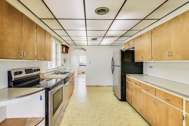 10117 Potter Rd, Des Plaines, IL 60016 - kitchen with appliances with stainless steel finishes, a sink, arched walkways, light floors, and light countertops