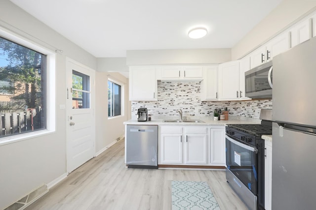 9002 N Clifton Ave, Niles, IL 60714 - kitchen with stainless steel appliances, a sink, light countertops, light wood-style floors, and white cabinetry
