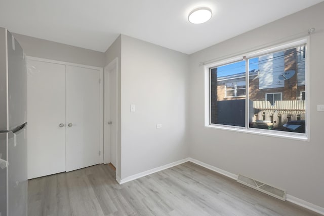 9002 N Clifton Ave, Niles, IL 60714 - unfurnished bedroom with freestanding refrigerator, light wood-type flooring, baseboards, and a closet