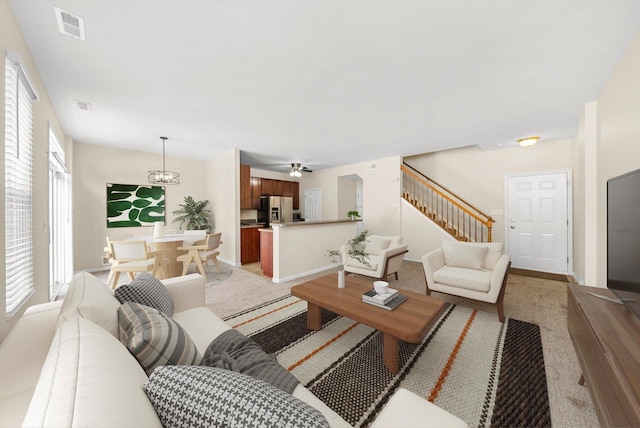 1133 Heron Cir, Joliet, IL 60431 - living room with light carpet, stairs, ceiling fan, and a chandelier
