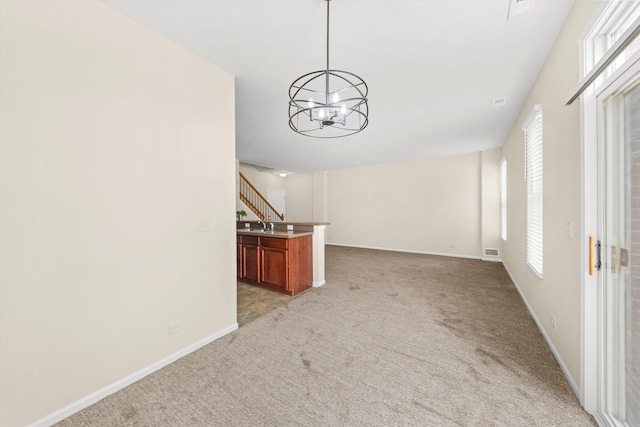 1133 Heron Cir, Joliet, IL 60431 - unfurnished living room featuring a chandelier, light colored carpet, baseboards, stairs, and a sink
