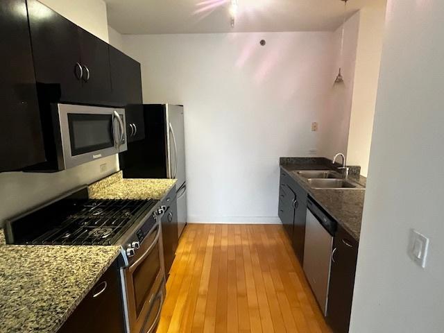 8 E Randolph St Unit 3206, Chicago, IL 60601 - kitchen featuring appliances with stainless steel finishes, a sink, light wood-type flooring, and dark stone counters