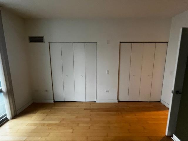 8 E Randolph St Unit 3206, Chicago, IL 60601 - unfurnished bedroom featuring multiple closets and light wood-type flooring