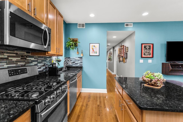 4872 N Kenmore Ave Unit 1, Chicago, IL 60640 - kitchen featuring stainless steel appliances, light wood-style flooring, backsplash, brown cabinets, and dark stone counters