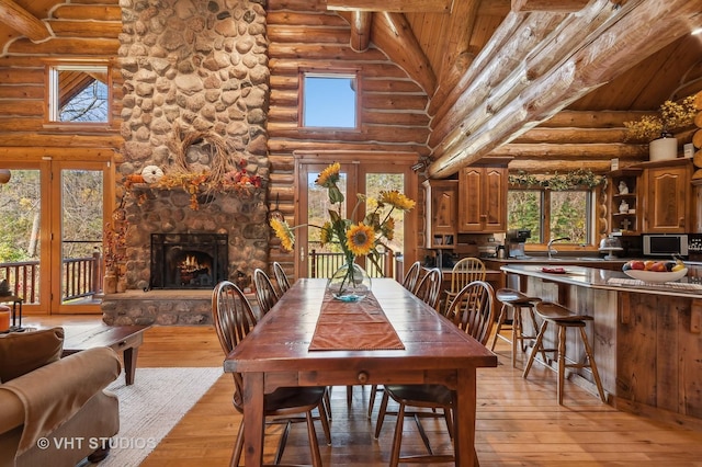2317 Paulson Rd, Harvard, IL 60033 - dining area featuring rustic walls, wooden ceiling with exposed beams, high vaulted ceiling, light wood-style floors, and a stone fireplace