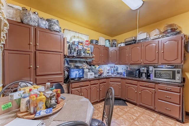 1032 S Maple Ave, Oak Park, IL 60304 - kitchen with stainless steel microwave, dark countertops, lofted ceiling, decorative backsplash, and light floors