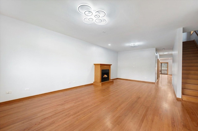 1019 W 47th Pl, Chicago, IL 60609 - unfurnished living room featuring stairs, light wood-type flooring, and a lit fireplace