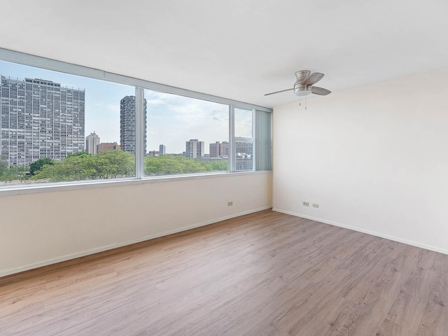 6301 N Sheridan Rd Unit 7G, Chicago, IL 60660 - spare room with wood finished floors, a city view, baseboards, and a ceiling fan