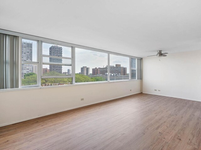 6301 N Sheridan Rd Unit 7G, Chicago, IL 60660 - unfurnished room featuring a view of city, wood finished floors, ceiling fan, and baseboards