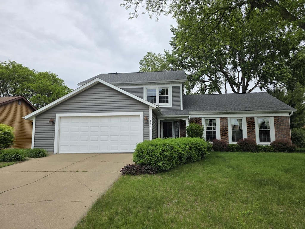 2206 11th Ave, Sterling, IL 61081 - traditional-style house with concrete driveway, a front yard, a garage, brick siding, and roof with shingles