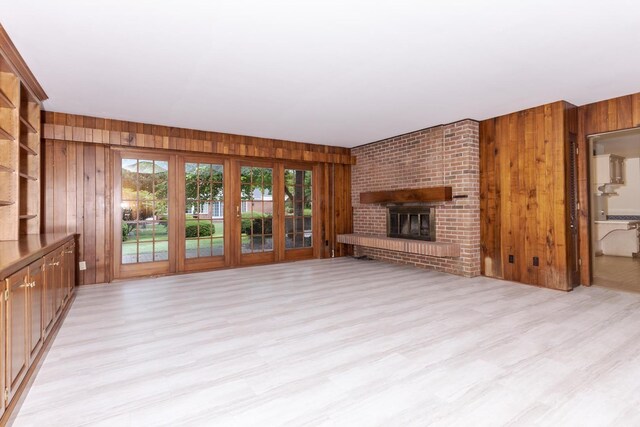 212 Mays Dr, Bloomington, IL 61701 - unfurnished living room featuring wood walls, light wood-style flooring, and a fireplace